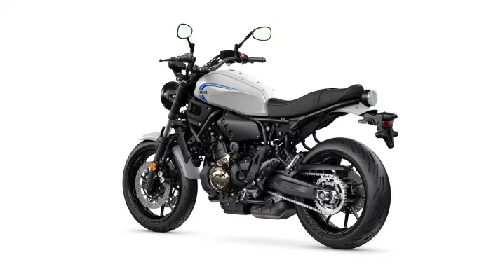 Side view of a white Yamaha motorcycle with blue stripe, showcasing the engine and frame on a white background.