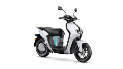 White and black scooter shown from a side angle with turquoise accent stripe on the body and large wheels.