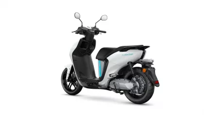 White and black scooter from a rear-side angle, showing the seat, body panels, and rear wheel.
