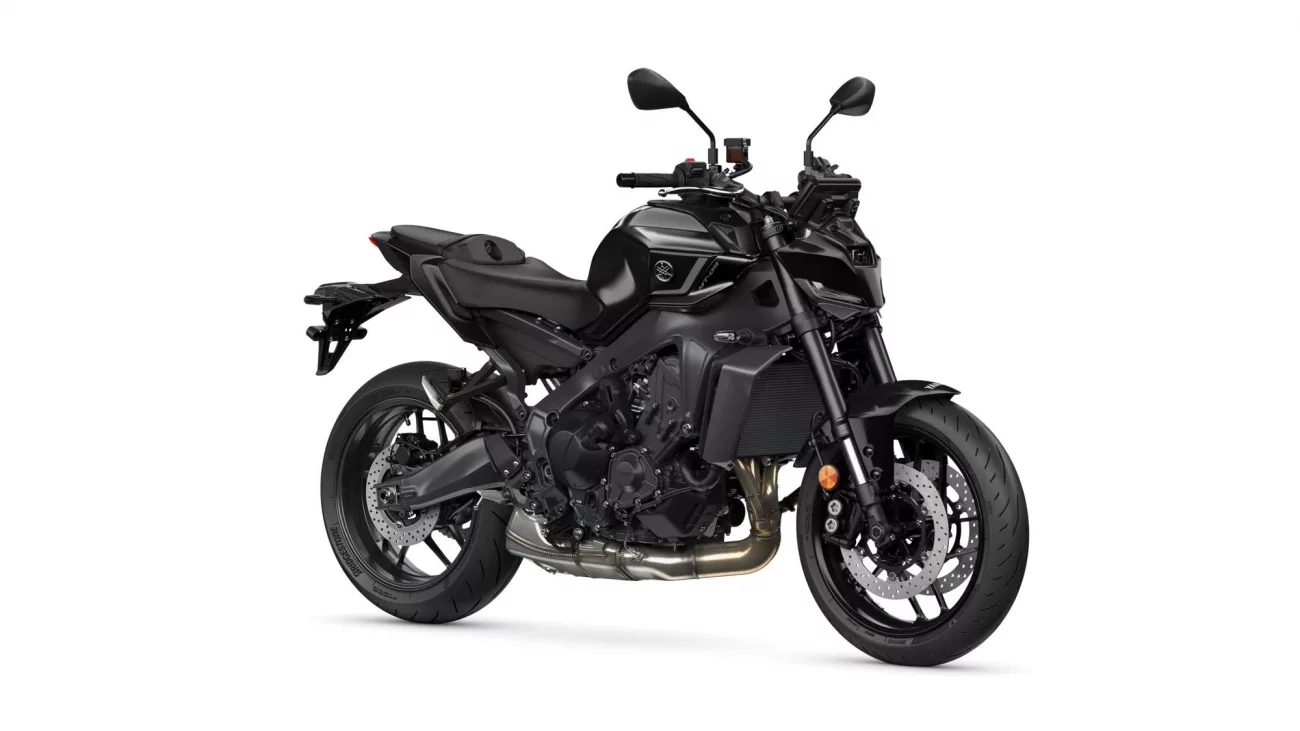 Black sport motorcycle photographed from the left side, showing engine, exhaust, and large disc brakes at the front and rear is visible beneath the frame.