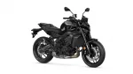 Black sport motorcycle photographed from the left side, showing engine, exhaust, and large disc brakes at the front and rear is visible beneath the frame.