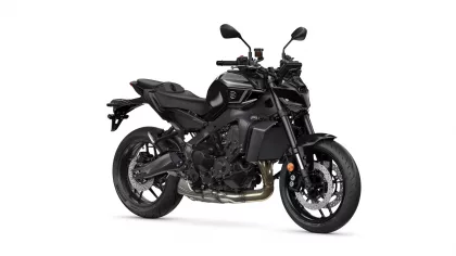 Black sport motorcycle photographed from the left side, showing engine, exhaust, and large disc brakes at the front and rear is visible beneath the frame.