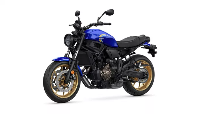 Blue Yamaha motorcycle photographed from the front-left, showing the round headlight and gold alloy wheels on a white background, product image.