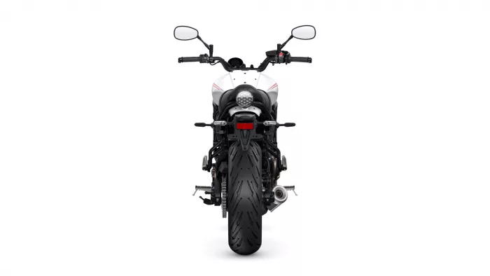 Rear view of a white motorcycle with black frame, twin exhausts, and round rear light.