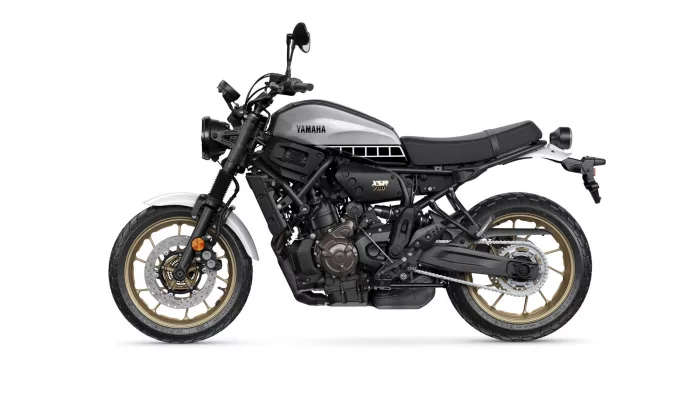 Side view of a Yamaha XSR700 motorcycle with a silver fuel tank, black frame, and gold alloy wheels.