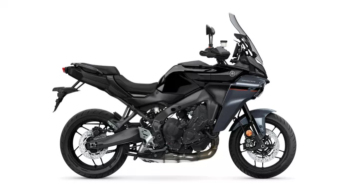 Side view of a black Yamaha Tracer sport-touring motorcycle with a tall windshield and visible front brake discs
