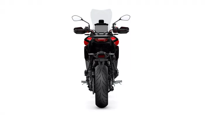 Rear view of a red and black adventure motorcycle with a tall windshield and wide rear tire.
