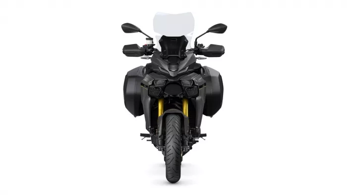 Front view of a dark adventure motorcycle with a tall windshield, dual headlights, and large side panniers on either side of the bike.
