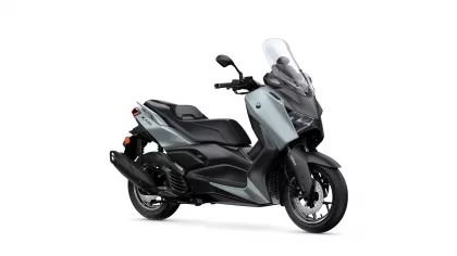 Side view of a silver and black Yamaha scooter with a tall windshield, shown facing right.