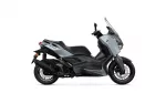 Side view of a gray Yamaha XMAX scooter with a tall windshield and black accents, shown in profile.