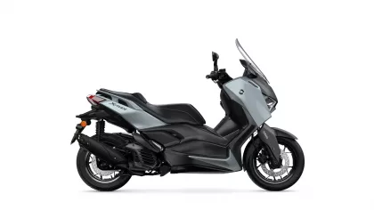 Side view of a gray Yamaha XMAX scooter with a tall windshield and black accents, shown in profile.