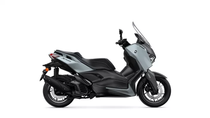 Side view of a gray Yamaha XMAX scooter with a tall windshield and black accents, shown in profile.