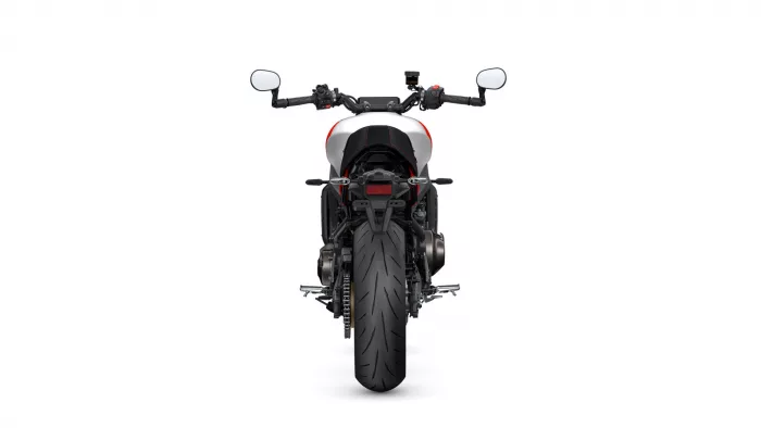Rear view of a modern sport motorcycle centered on a white background, showing a wide rear tire, red-accented white body, and black seat.
