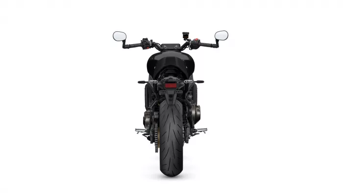 Rear view of a black sport motorcycle, focusing on the wide rear tire and tail section with mirrors visible at the handlebars