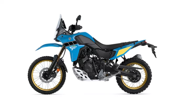 Side view of a blue Yamaha Tenere 700 Rally adventure motorcycle with gold wheels against a white background on display.