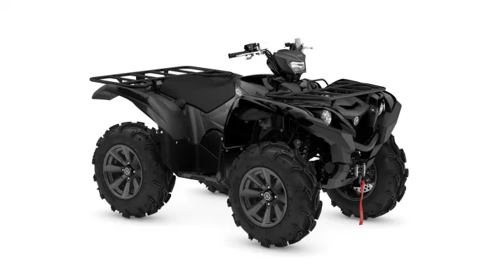 Black quad bike/ATV with large knobby tires, front cargo rack, and red tow strap visible, photographed from a side-angle.