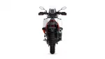 Rear view of a white adventure motorcycle with red accents, large knobby rear tire, and visible exhaust on the right side against a white background.