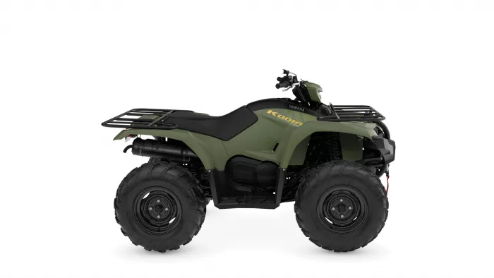 Green Yamaha Kodiak all-terrain vehicle with front and rear cargo racks and large off-road tires shown in a three-quarter view.