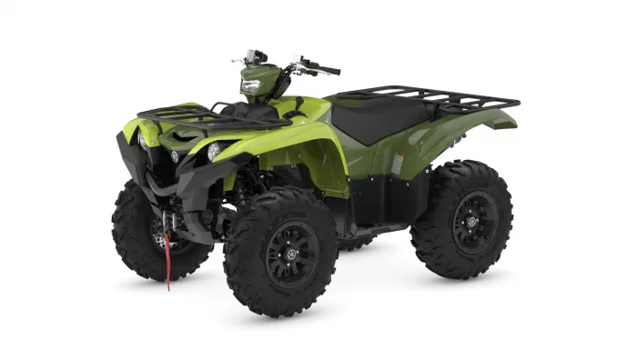 Green ATV with black rack and large knobby tires, viewed from the front-right.
