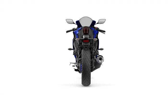 Rear view of a blue sport motorcycle on a white background, showing taillight, exhaust, and wide rear tire.