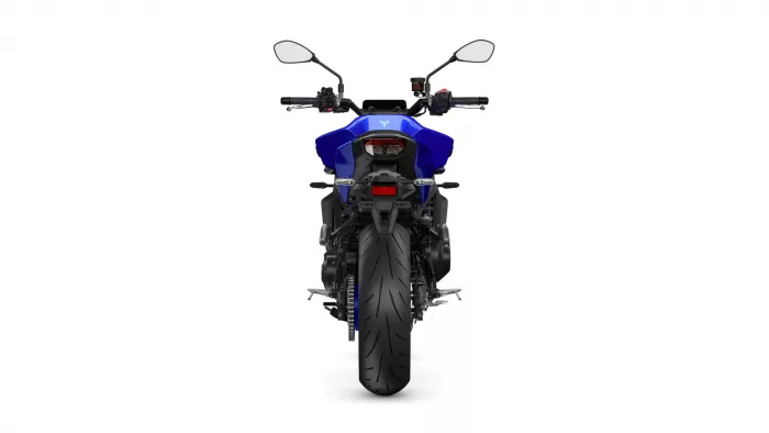 Rear view of a blue sport motorcycle, showing the wide rear tire, taillight, and mirrors behind the rider position
