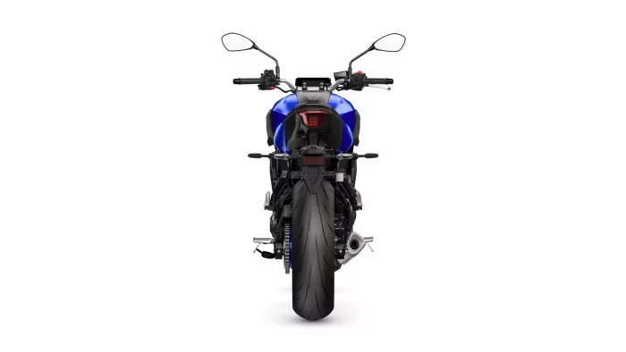 Rear view of a blue motorcycle showing tail light, seat, and rear tire against a white background