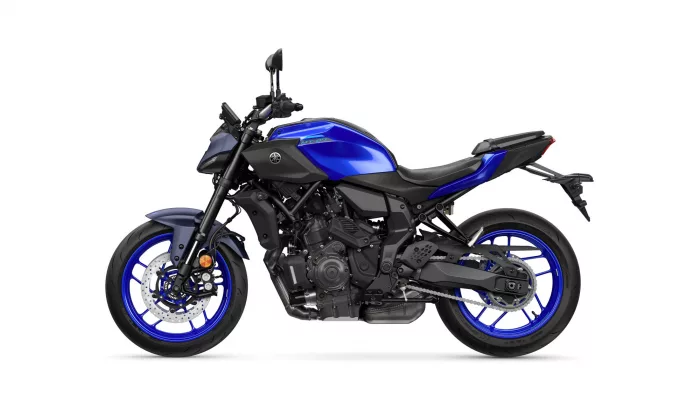 Left-side view of a blue Yamaha MT-07 sport motorcycle with black frame and bright blue rims, shown against a white background, highlighting the engine and exhaust.