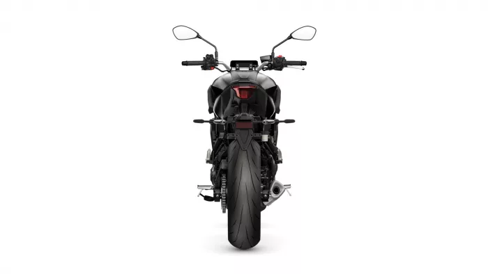 Rear view of a black sport motorcycle with a red taillight and wide rear tire, facing away from the viewer