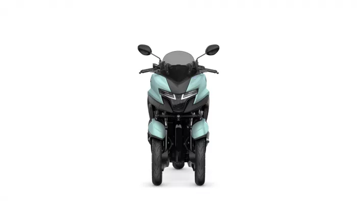 Front view of a teal motorcycle with a dark windshield and handlebars, facing the viewer.