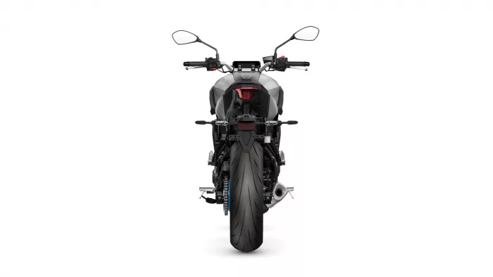 Rear view of a modern sport motorcycle featuring a red taillight and wide rear tire, seen from behind on a white background.