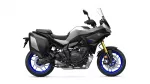 Profile view of a Yamaha Tracer GT sport-touring motorcycle with black/gray body, large windshield, and blue rims.