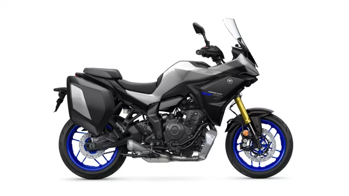 Profile view of a Yamaha Tracer GT sport-touring motorcycle with black/gray body, large windshield, and blue rims.