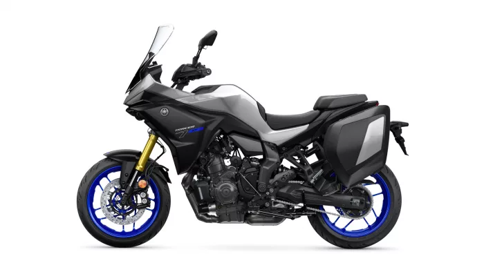 Side view of a Yamaha Tracer 7 GT sport-touring motorcycle with black-gray body, blue wheels, and hard panniers on both sides.