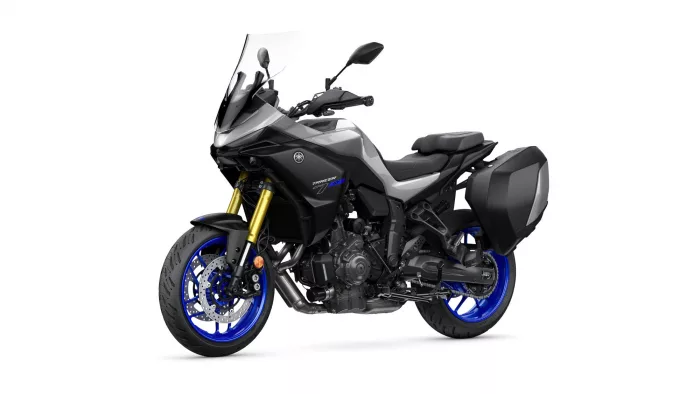 Yamaha Tracer 9 GT sport-touring motorcycle with a tall windshield, black-gray body, and blue alloy wheels with side panniers (left-side view).
