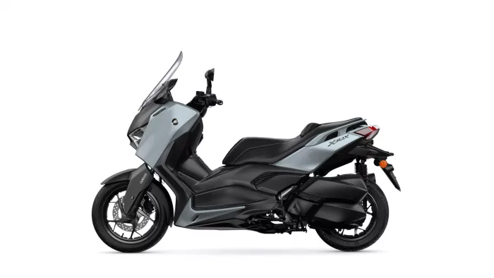 Side view of a Yamaha XMAX scooter in gray and black against a white background, showing front fairing and seat.