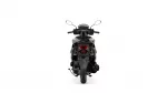 Rear view of a black motorcycle with a red taillight and cargo rack seen from behind, on a white background.