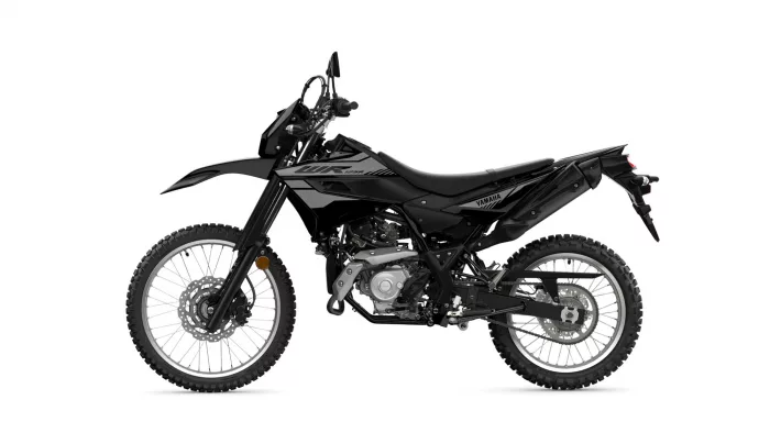Side view of a black Yamaha dirt bike with knobby off-road tires and exposed engine details, ready for trail riding.