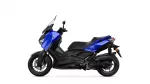 Blue Yamaha XMAX scooter viewed from the left side, showing its blue body panels, black chassis, windshield, and front wheel with disc brake exit.