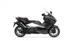 Side view of a black Yamaha Tmax maxi-scooter with a tall windshield and red seat accents.