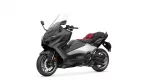 Black and gray Yamaha Tmax motorcycle scooter with a red seat, angled to the left, showing its windshield and front headlight.