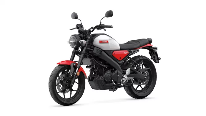 Yamaha motorcycle shown in a white-and-red color scheme, front three-quarter view with round headlight and black frame on white background