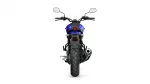 Rear view of a blue motorcycle showing chunky rear tire, single round red taillight, and dual side mirrors from the rider position