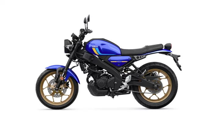 Blue Yamaha motorcycle in a left-side profile with gold alloy wheels and black frame on a white background
