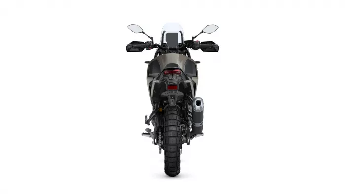 Rear view of a rugged adventure motorcycle showing wide rear tire, taillight, and exhaust on the right side behind the seat area
