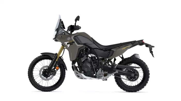 Side profile of an olive Yamaha Tenere 700 adventure motorcycle on a white background with knobby tires and gold front forks