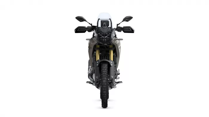 Front view of a modern adventure motorcycle with a tall windscreen, dual headlights, and gold inverted forks on a white background; rugged tire in view.