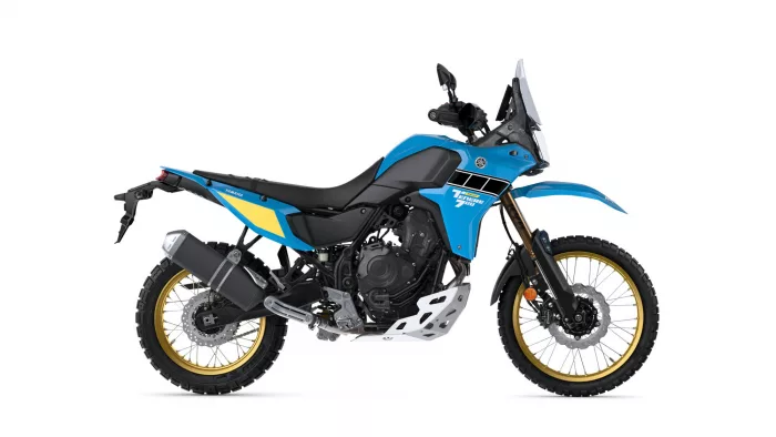 Blue Yamaha Tenere 700 adventure motorcycle shown in a side profile with a tall windscreen and off-road tires on gold rims.