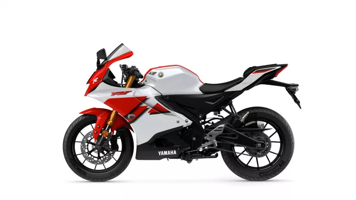 Side view of a red and white Yamaha sport motorcycle against a white background with black seat and gold front forks.