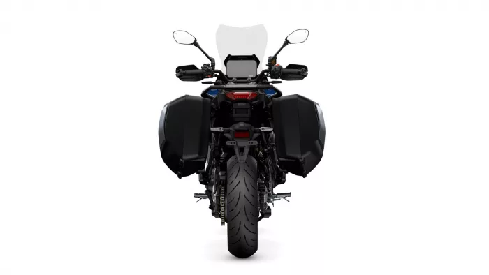 Rear view of a black touring motorcycle with large side panniers and a windscreen against a white background, showing taillight and rear tire.