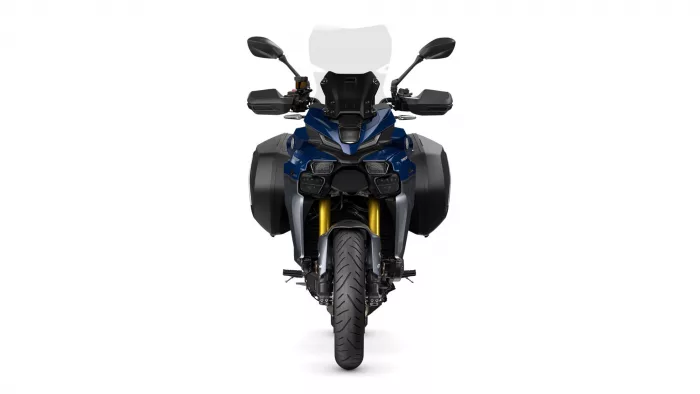 Front view of a blue adventure motorcycle with a tall windshield, side panniers, and gold front forks
